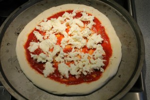 Kecskesajtos pizza készítése: passzírozott paradicsom, oregánó, só, olívaolaj és mozzarella alkotják a pizzaszószt