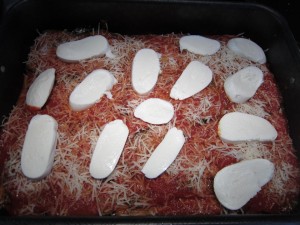 Parmigiana di melanzane rétegzése: reszelt parmezán és szeletelt mozzarella vagy scamorza