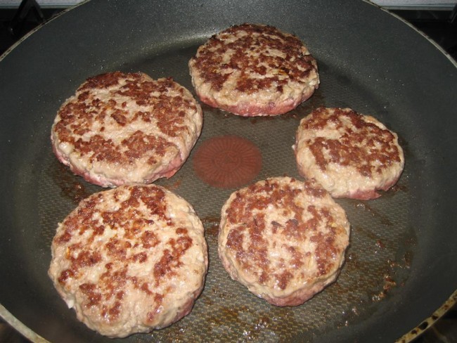 Hagyományos hamburger húspogácsa sütése serpenyőben